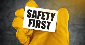 gloved hand holding safety first placard