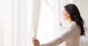 woman opening curtains